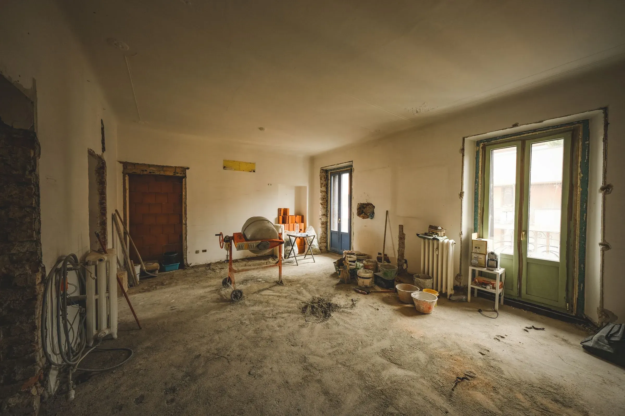 Entkernte Altbauwohnung mit freigelegtem Estrich, Mörtelmischer und Werkzeug