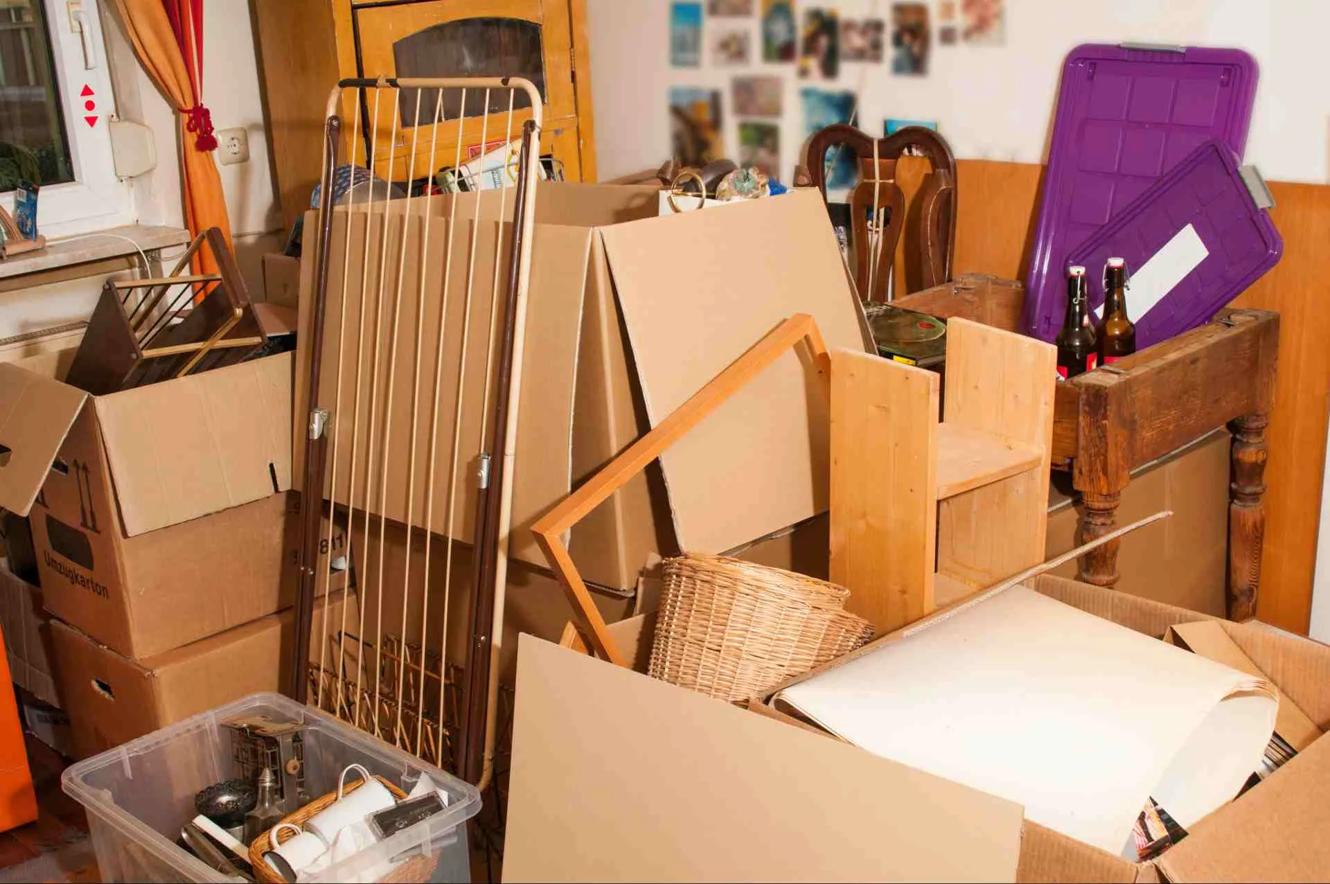 Vollgestelltes Zimmer mit Kartons, Möbeln und Kisten vor der Entrümpelung