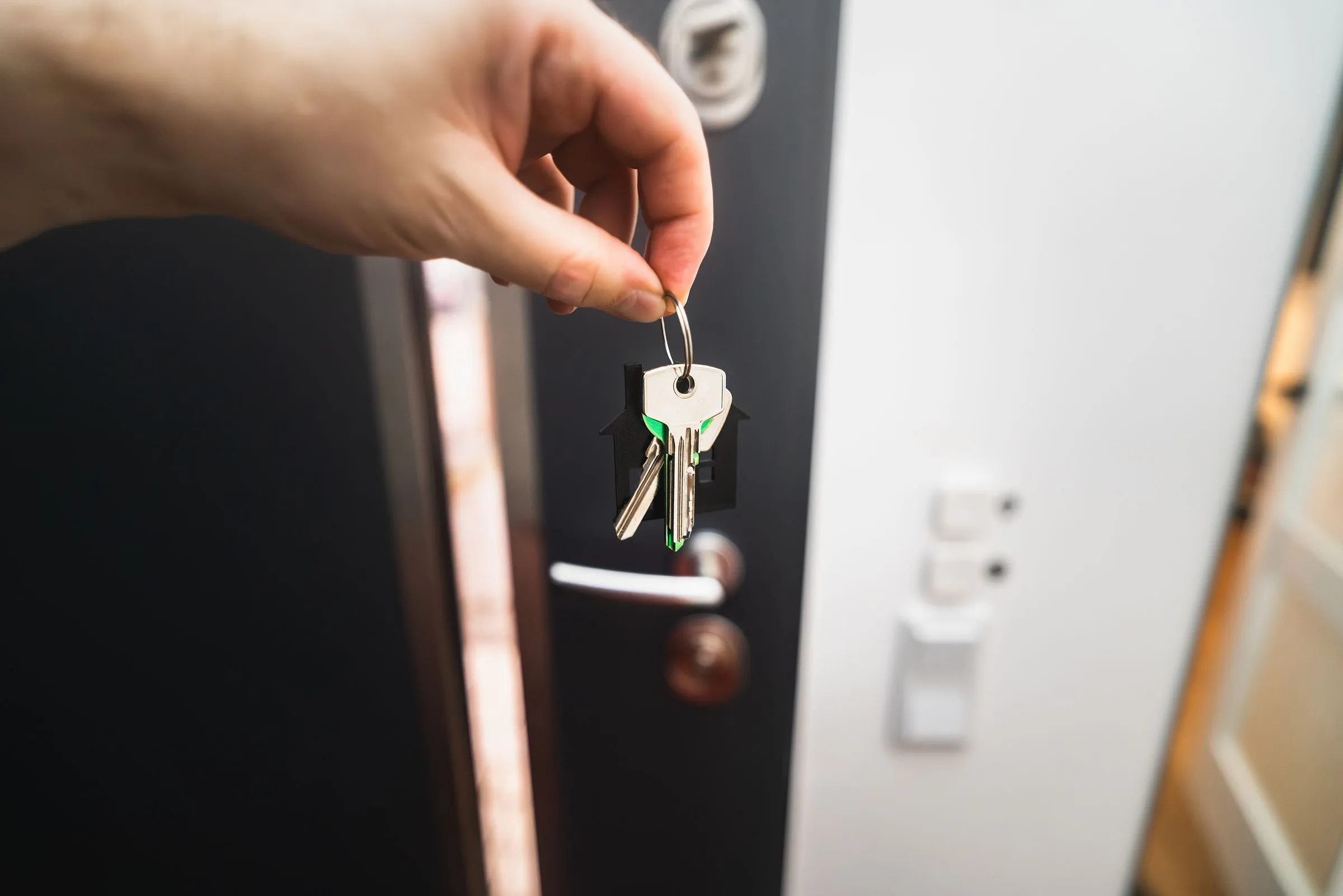 Hand mit Schlüsselbund vor einer geöffneten Wohnungstür