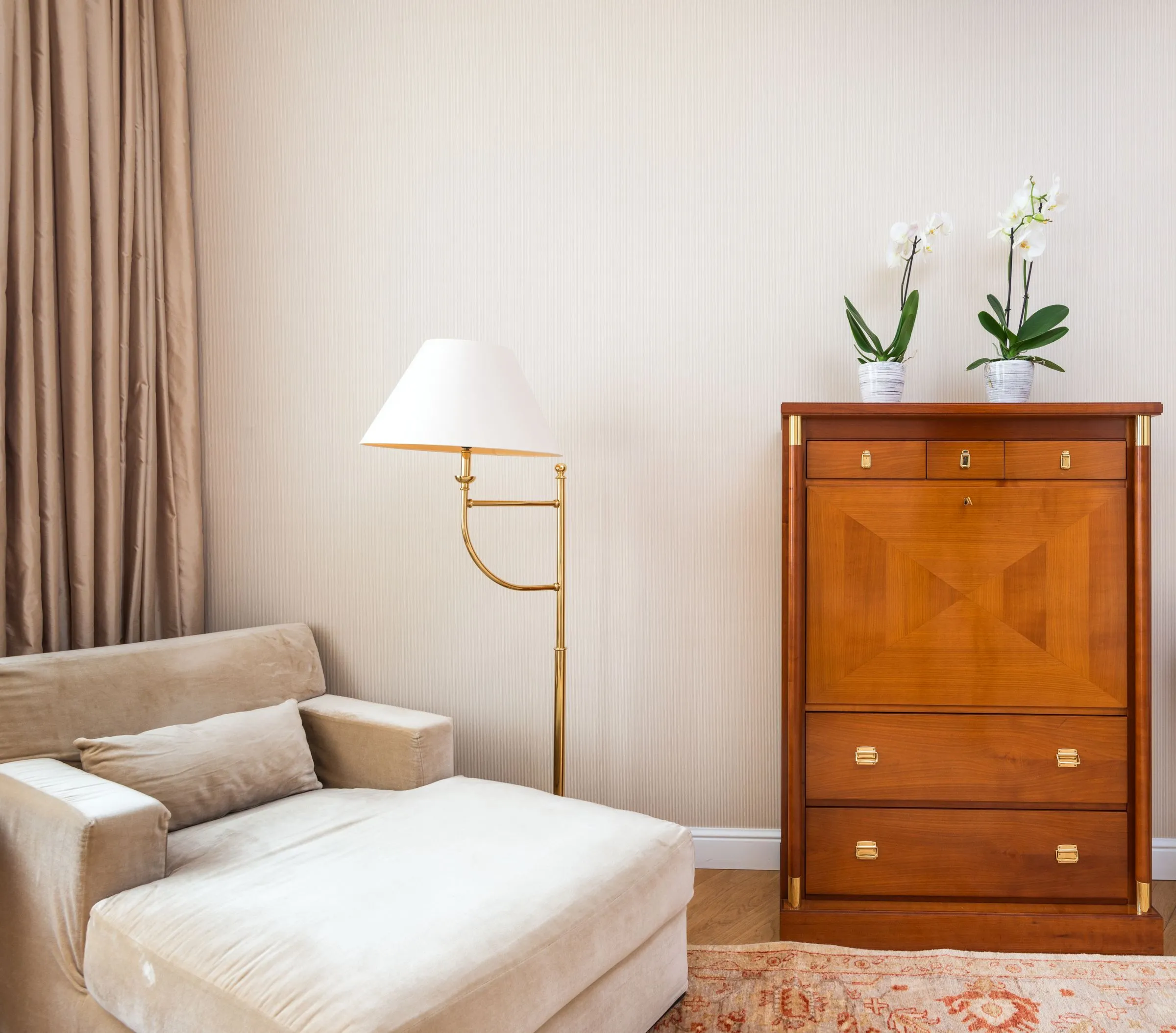 Ruhiges Zimmer mit Polstersofa, Stehlampe und Sekretär mit Orchideen